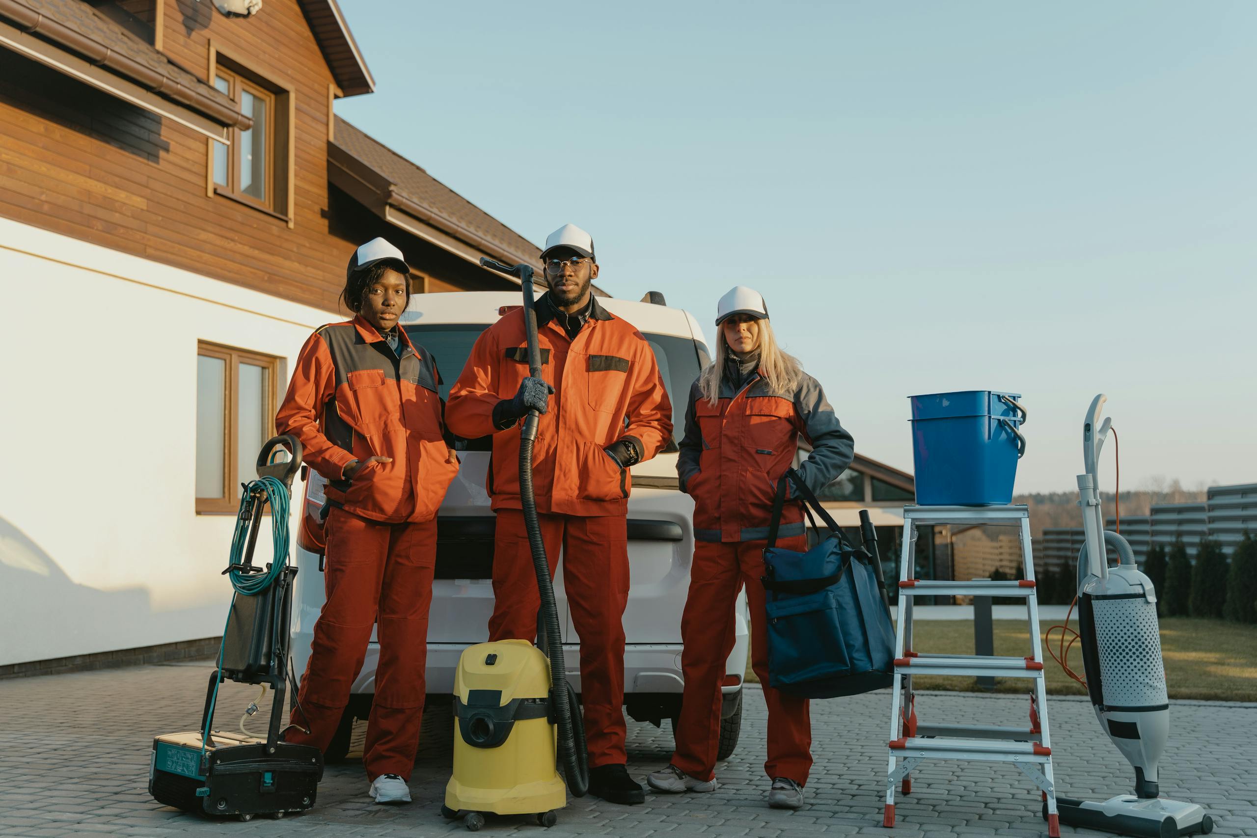 3 Men in Orange Jacket and Helmet Standing Beside White and Yellow Water Jug